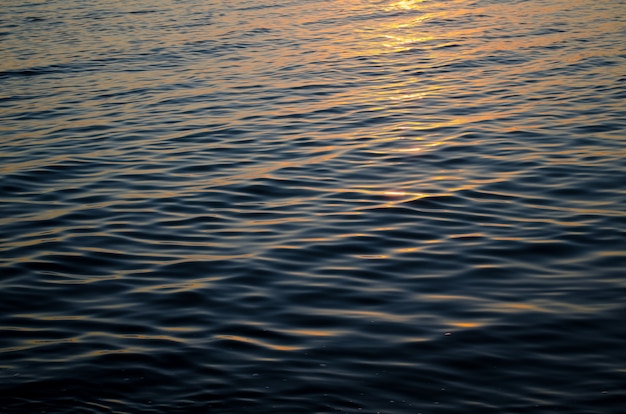 Texture de l'eau de mer au coucher du soleil, couleurs bleues et orange du chemin du soleil