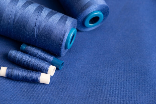 Texture de fil bleu en bobine pour la couture sur un fond bleu plain couture de vêtements de près
