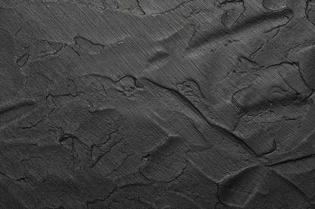 Texture de fond abstrait noir de surface grunge inégale avec des coups de pinceau de plâtre et de peinture