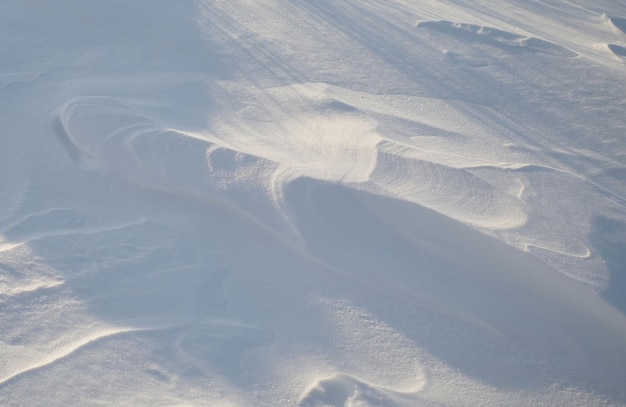 Texture de fond blanc brillant de neige naturelle avec des traces de vent ondulées