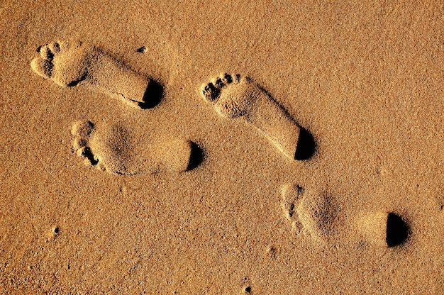 Texture de fond Empreintes de pieds humains sur le sable près de l&#39;eau sur la plage.