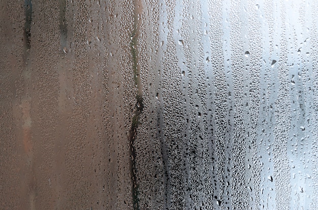 Photo texture d'une goutte de pluie sur un fond transparent humide au verre. tonique de couleur grise