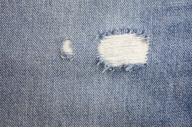 Texture de jeans en denim déchiré bleu.