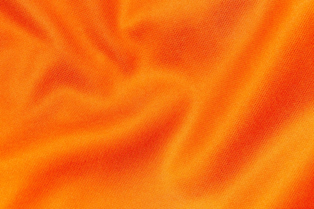 Texture de jersey de maillot de football en tissu de vêtements de sport de couleur orange et fond textile.