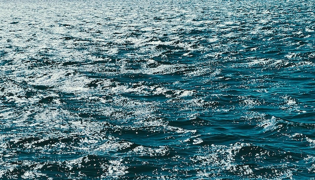 La texture de la mer et le concept de nature côtière l'eau de l'océan bleu comme fond de surface qui coule des vagues et des somm...