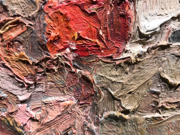 Texture multicolore lumineuse avec une tache rouge au centre peinture acrylique sur toile palette taches de peinture mélangées à de l'eau la texture est hétérogène volumineuse l'arrière-plan