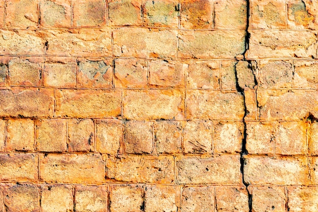 Texture d'un mur de briques avec des fissures et des rayures qui peuvent être utilisées comme arrière-plan