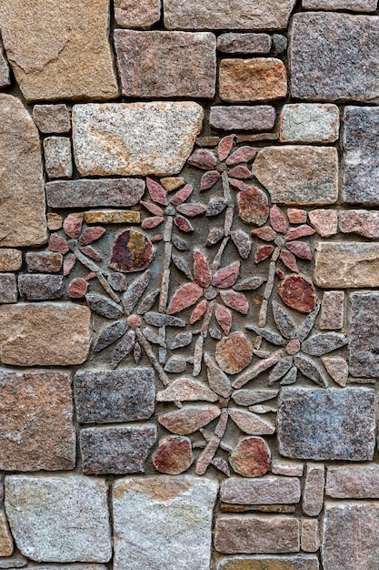 Texture de mur en pierre Fleurs disposées en pierre sur un mur de pierre.