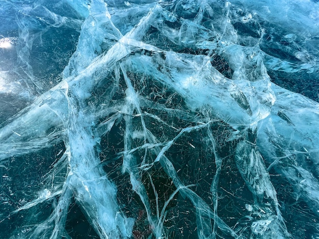 La texture naturelle de la glace d'hiver avec des bulles blanches et des fissures sur un lac gelé Résumé historique de la glace et des fissures à la surface du lac Baïkal gelé