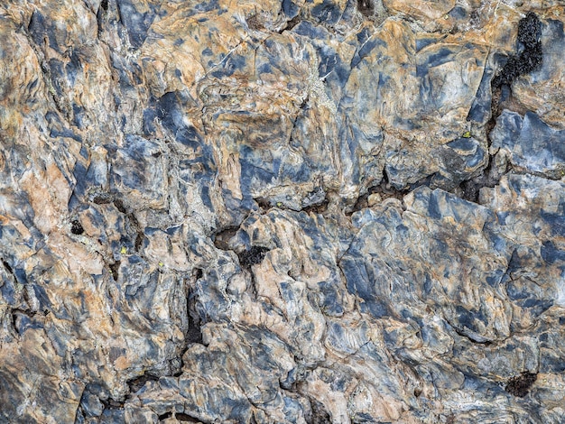 Texture ondulée de la pierre. Texture détaillée multicolore d'une pente de montagne rocheuse. Roche géologique.