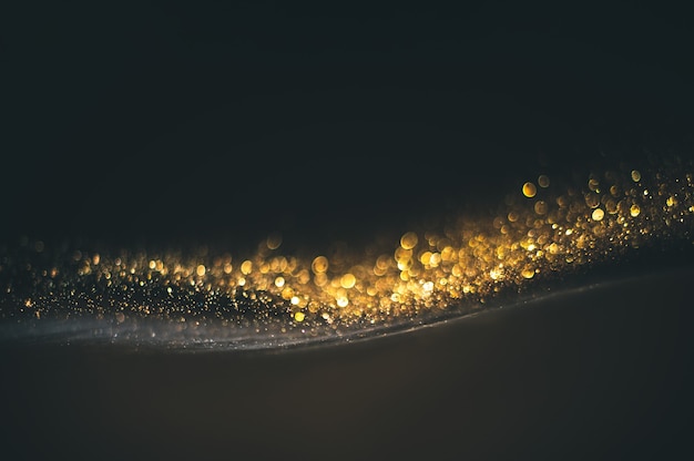 Texture de paillettes d'or sur fond noir. Texture abstraite granuleuse dorée sur fond noir. Élément de conception.