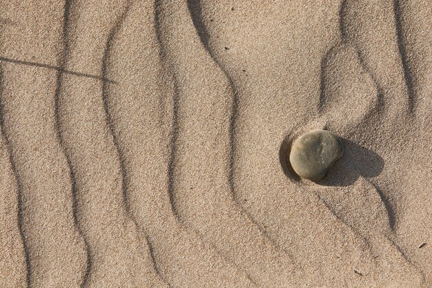 Texture de sable nivelé par le vent avec quelques cailloux