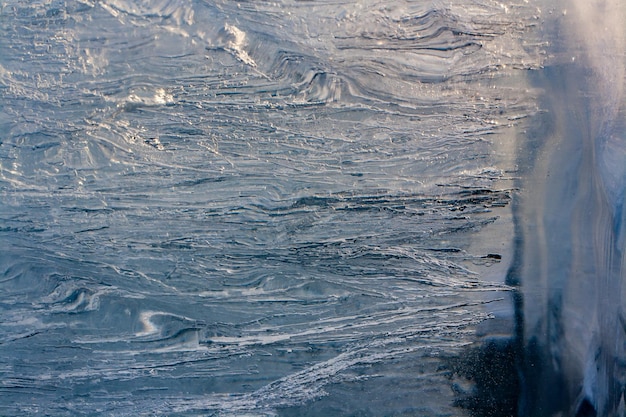 La texture de la structure de l'épaisse fonte des glaces du lac Baïkal. Des bulles d'air et de longs cordons minces de glace fondue. Mise au point sélective sur les extrémités des chaînes. Horizontal.