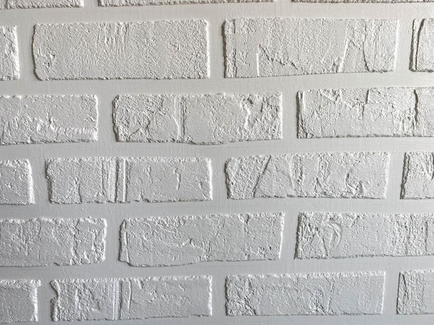 La texture de surface d'un mur de briques de style loft blanc fait maison avec des joints de briques en gypse