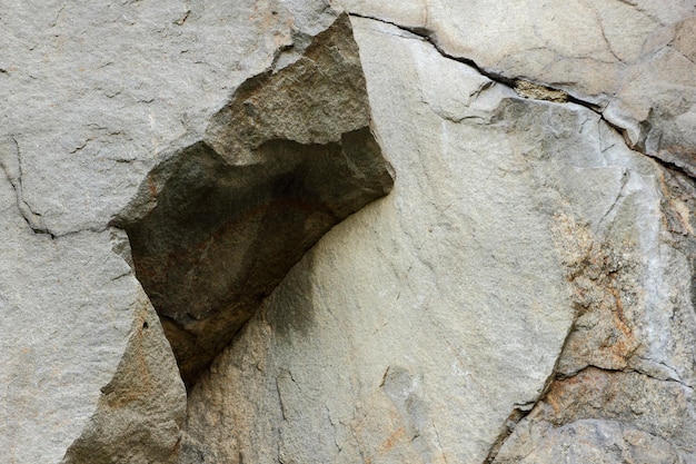La texture de la surface de la vieille pierre altérée par les intempéries Détail de la nature des rochers Mur de pierre brun rugueux Gros plan