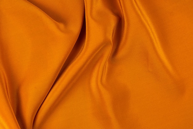 La texture de tissu de luxe en soie ou satin doré peut être utilisée comme fond abstrait