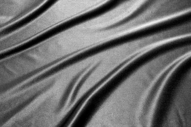 La texture d'un tissu de soie noir froissé. Motif satiné abstrait