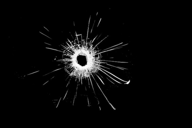 Photo texture de verre brisé. trou d'une balle sur fond noir.