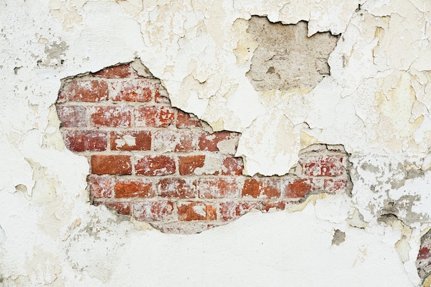 Texture d'un vieux mur de briques avec du plâtre endommagé et de la peinture fissurée