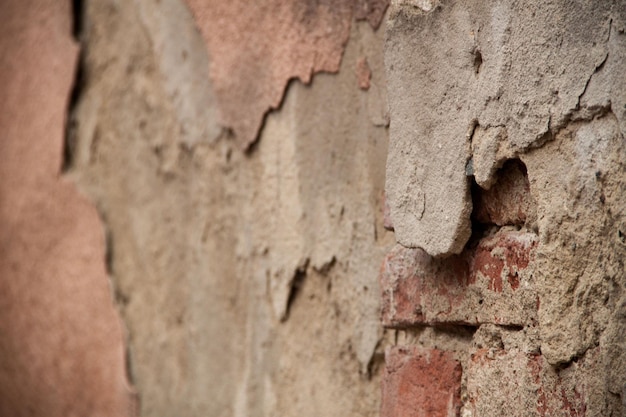 Texture d'un vieux mur en lambeaux Arrière-plan de vieilles briques et fissures dans le plâtre Tons jaunes et bruns