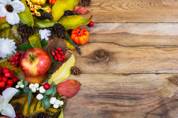 Photo thanksgiving voeux avec citrouille, pommes, feuilles d'automne, des cônes et des fleurs blanches