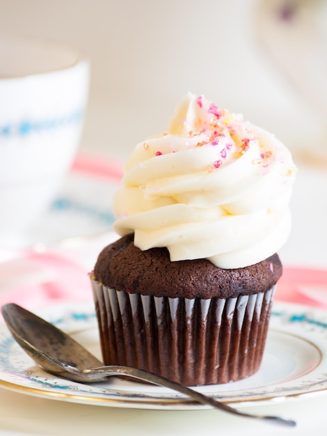 Thé de l'après-midi servi avec un cupcake blanc.