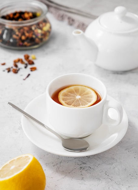 Thé au citron dans une tasse blanche sur fond clair avec une théière Le concept d'un petit-déjeuner sain et savoureux pour l'immunité