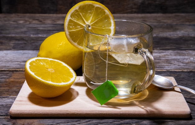 Thé au citron dans un verre sur un fond en bois.