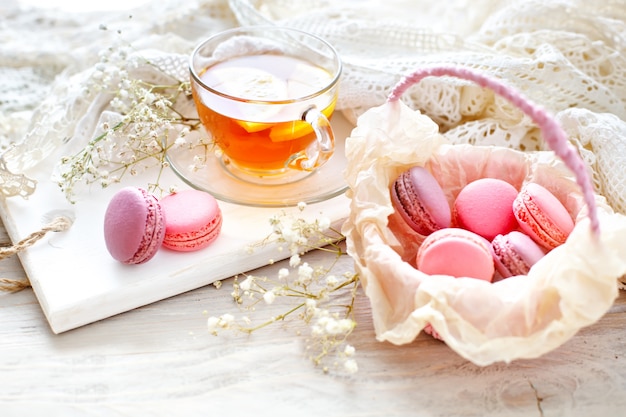 Thé au citron, fleurs sauvages et macaron sur table en bois blanc