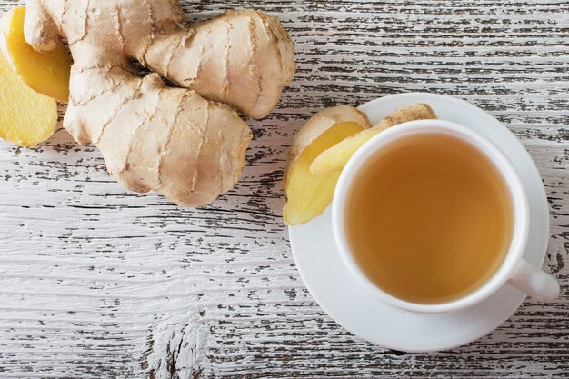 Thé au gingembre dans une tasse blanche sur fond de bois