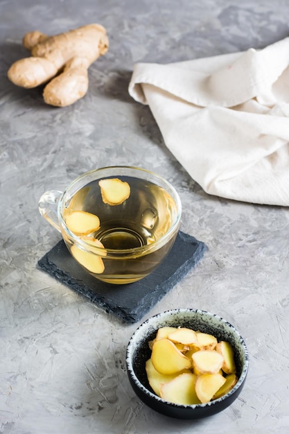 Thé au gingembre dans une tasse et racine hachée dans un bol sur la table Vitamines naturelles Vue verticale