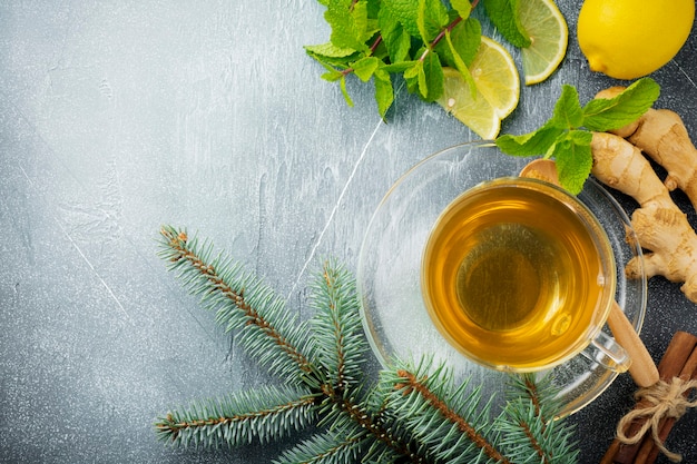 Thé au gingembre utile à la menthe, au citron et au sucre dans une tasse transparente sur un béton bleu.