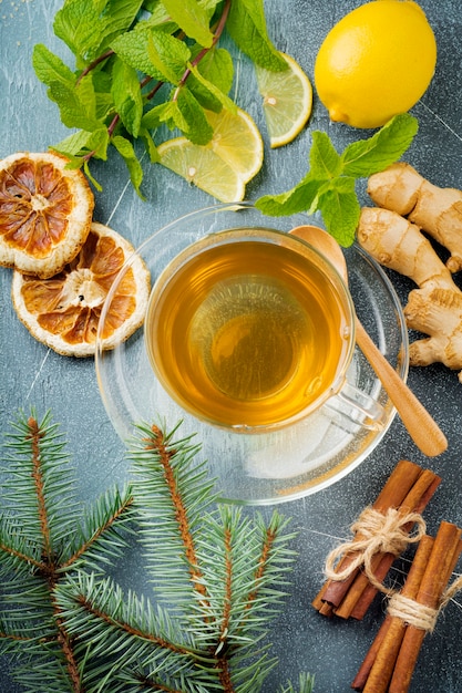 Thé au gingembre utile à la menthe, au citron et au sucre dans une tasse transparente sur un béton bleu.