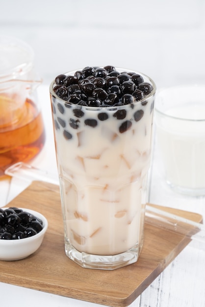 Thé au lait à bulles avec garniture de perles de tapioca, célèbre boisson taïwanaise sur table en bois blanc