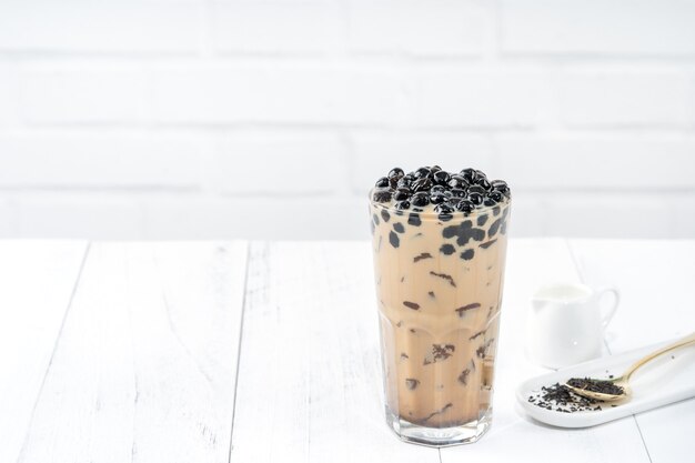 Thé au lait à bulles avec garniture de perles de tapioca, célèbre boisson taïwanaise sur table en bois blanc