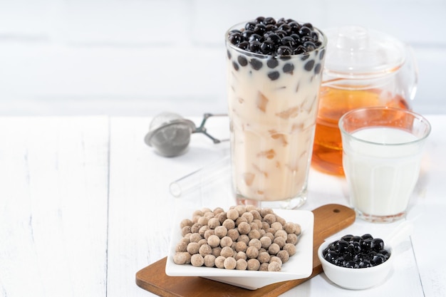 Thé au lait à bulles avec garniture de perles de tapioca ingrédient célèbre boisson taïwanaise sur fond de table en bois blanc dans un verre à boire gros plan copie espace