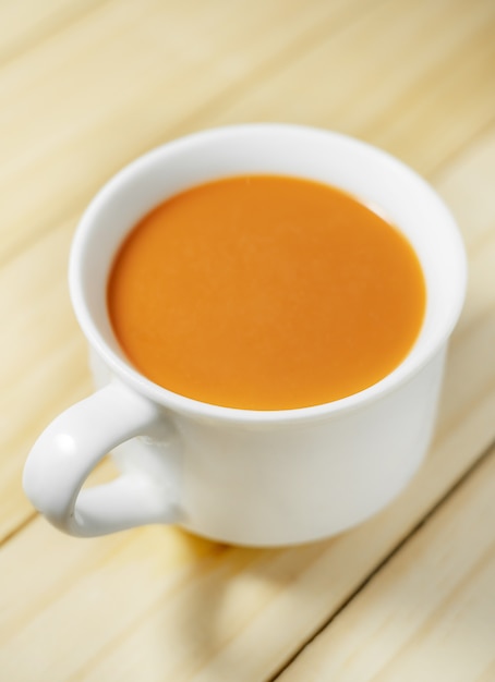 Thé au lait chaud dans une tasse blanche en bois