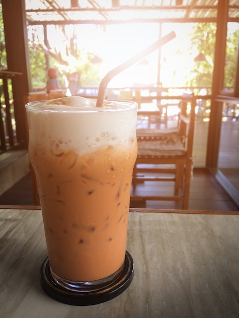 Thé au lait glacé sur une table en bois au café. Ton Vintage