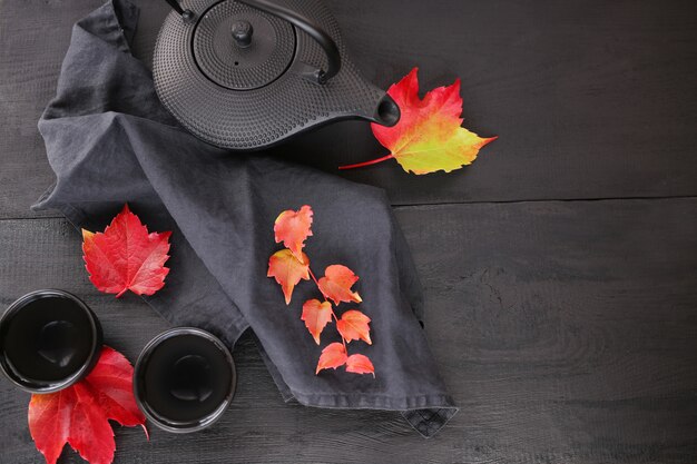 thé d'automne dans un style minimaliste. théière noire en style asiatique et feuilles d'automne lumineux