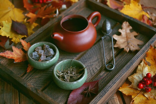 Thé d'automne, théière sur un fond en bois avec des feuilles d'automne