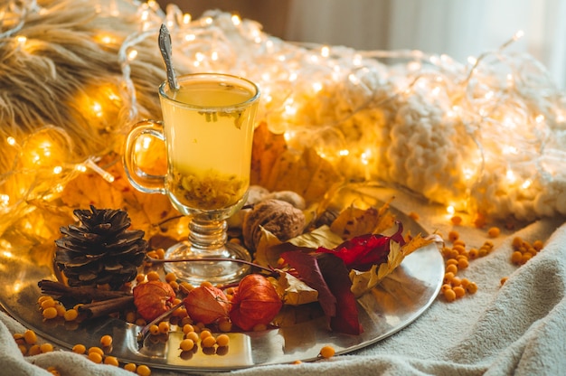 Thé aux baies d'argousier et au gingembre sur de vieux livres, miel, bougie et feuilles d'automne. L'atmosphère de confort à la maison. Accueil chaleureux et confortable.