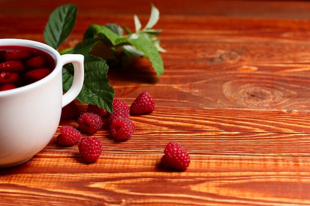 Thé aux framboises et baies à côté d'une tasse, sur une table en bois vintage.