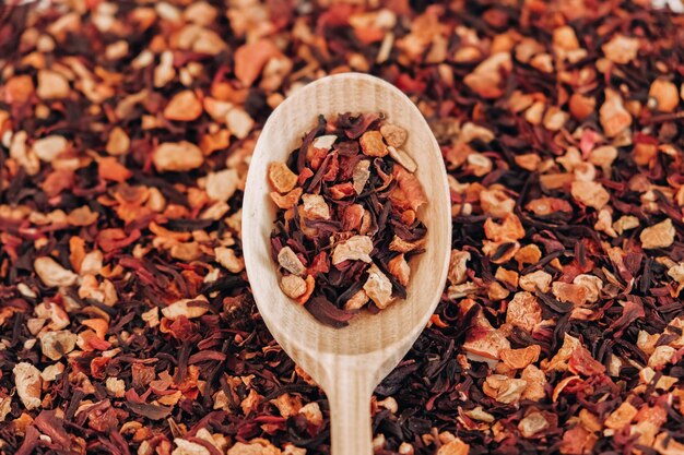 Thé aux fruits secs dans une cuillère en bois comme texture de fond. Vue de dessus. Copie, espace vide pour le texte