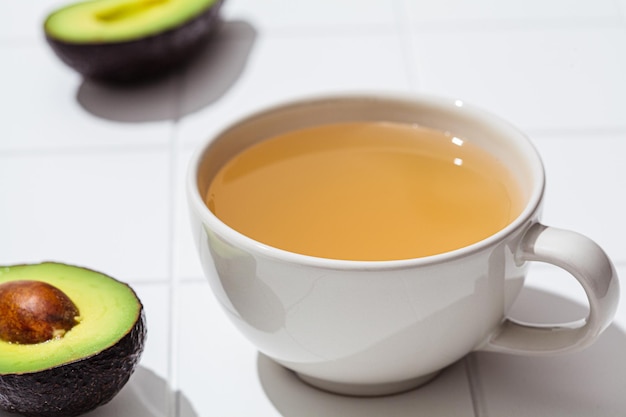 Thé aux graines d'avocat dans une tasse blanche fond blanc Tendance végétalienne