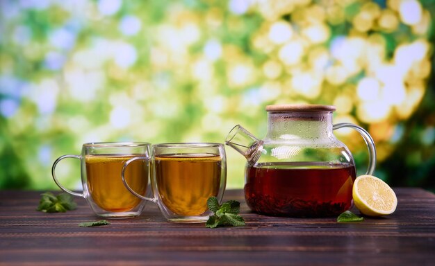 Thé à base de plantes biologique naturel dans une théière en verre et une tasse sur une table en bois