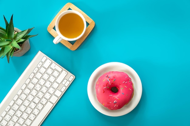 Thé en beignet et clavier sur fond bleu à plat