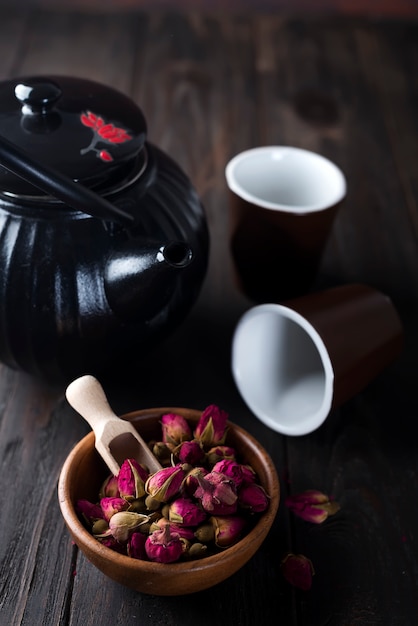 Thé de boutons de rose sur un bol en bois avec théière