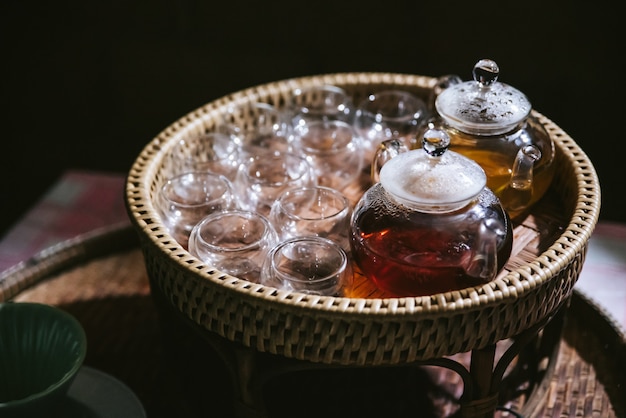 Thé de camomille chaud dans une théière en verre avec des verres vides dans un panier pour les testeurs.