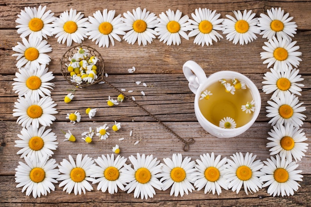 Thé à la camomille sur fond en bois. Dans un cadre de fleur