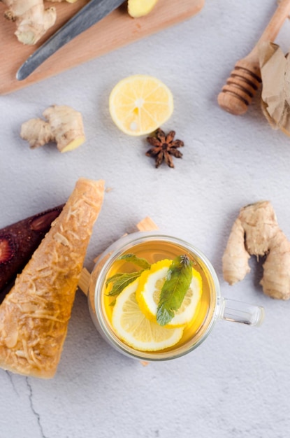 Thé chaud au citron et à la menthe dans une tasse en verre avec pastille de fruits secs